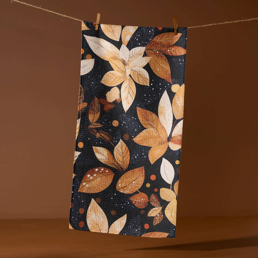 Fabric with autumn leaf pattern hanging on a line against a brown background