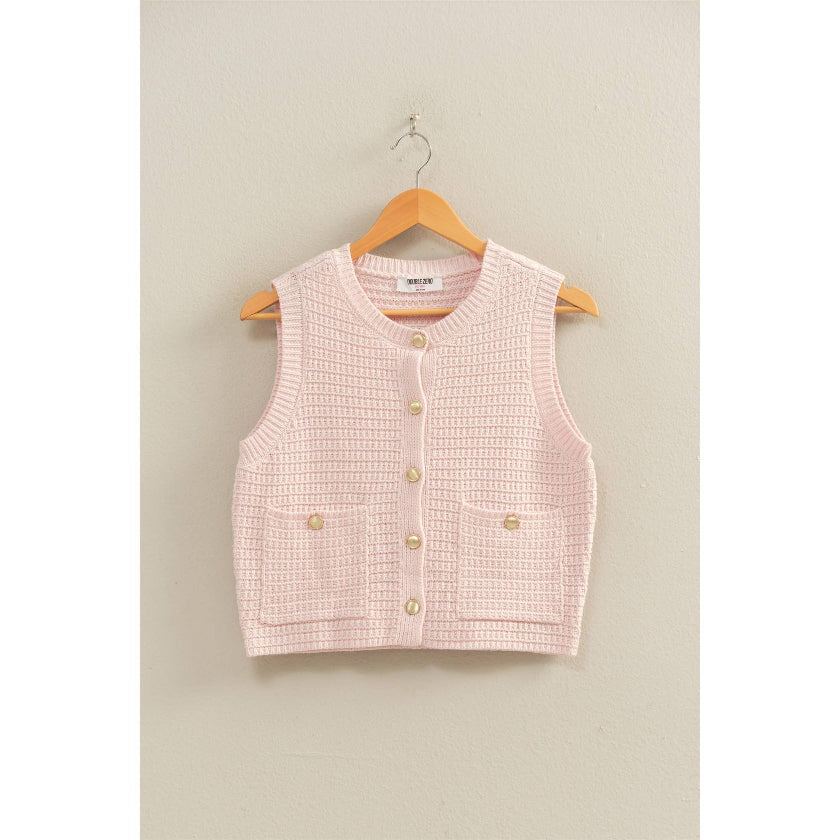 Pink checkered vest with gold buttons on a hanger against a beige wall