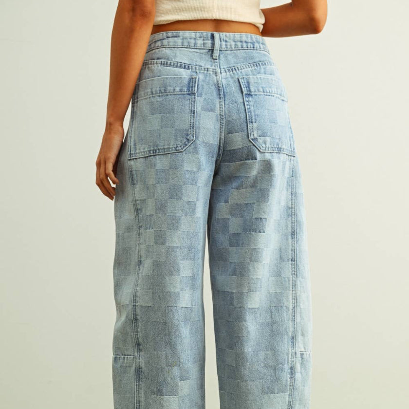 Person wearing checkered jeans on a green floor with a white wall background