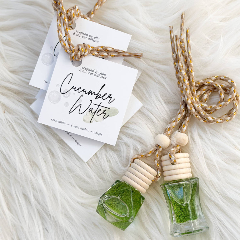 Two small bottles with green liquid and wooden necklaces on a fluffy white surface