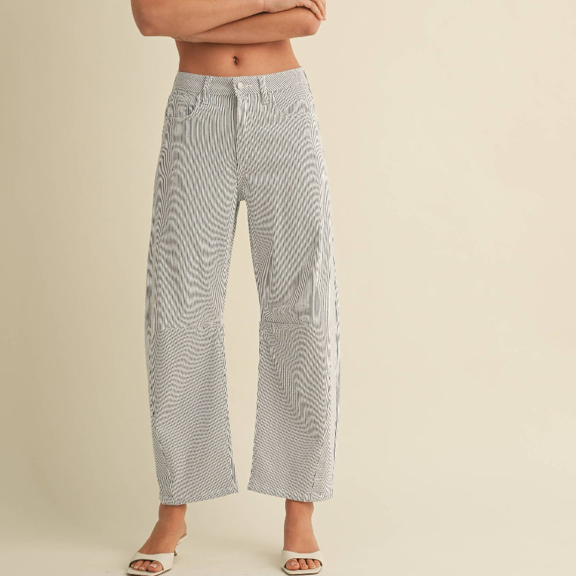 Woman wearing a white sleeveless top and light gray wide-leg jeans on a beige background