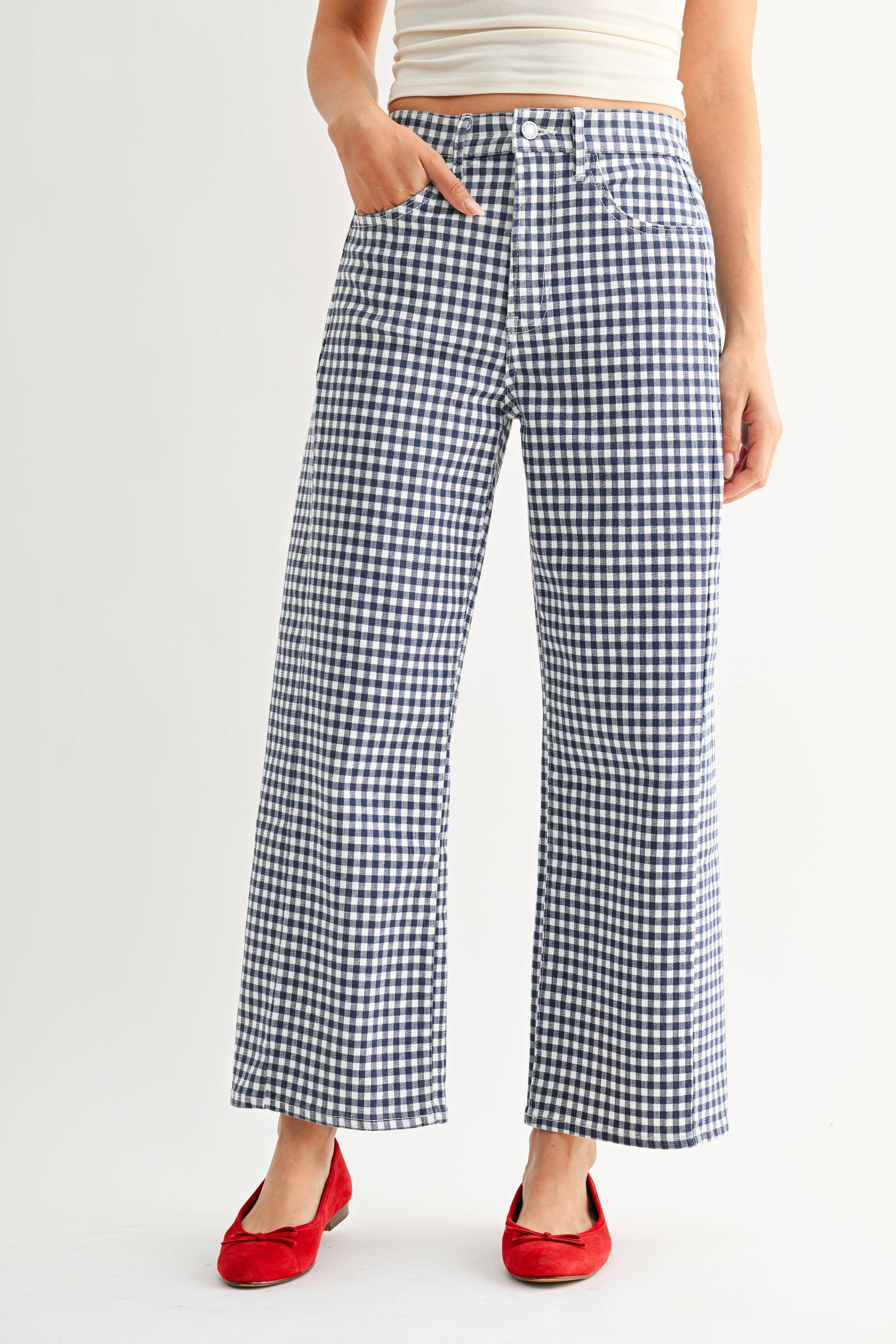 Person wearing blue and white checkered pants with red shoes on a light gray background