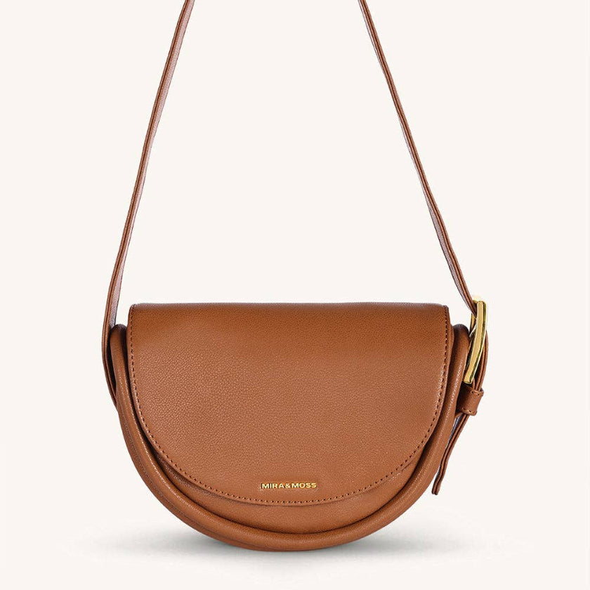 Brown leather handbag with a strap on a light gray background