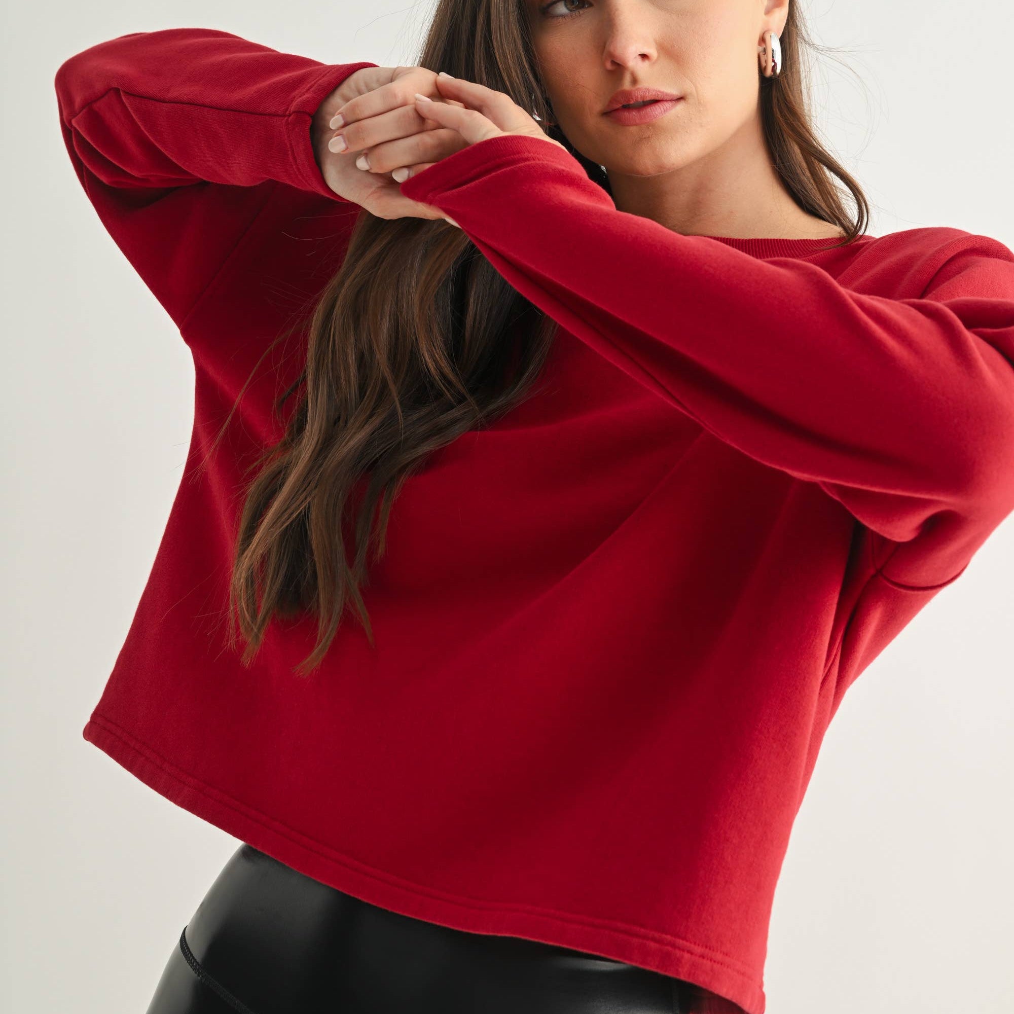 Woman wearing a red sweater and black pants against a white background