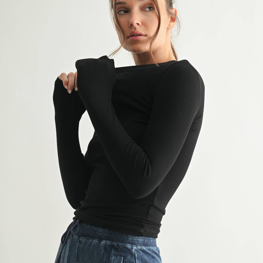 Woman wearing a black long-sleeve top and blue jeans on a white background