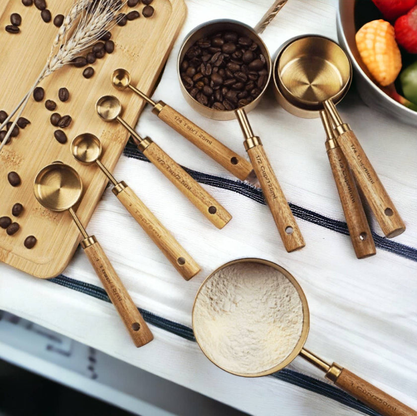 Set of wooden-handled measuring spoons with coffee beans on a white surface