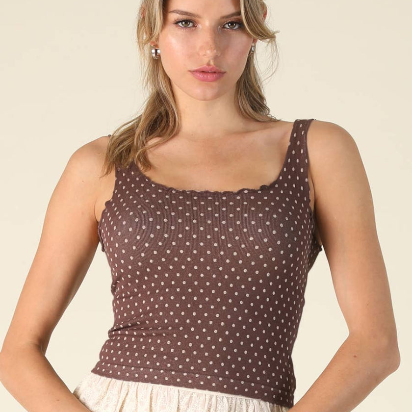 Woman wearing a brown polka dot tank top against a beige background