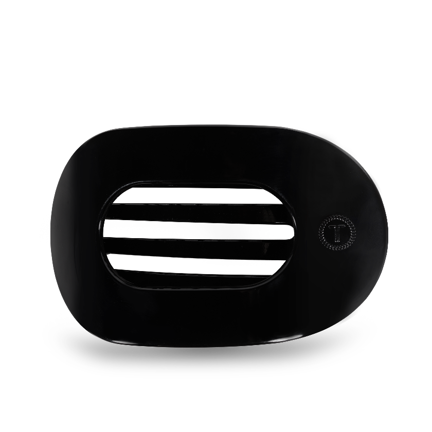 A black, round flat hair clip with a logo on the top center.