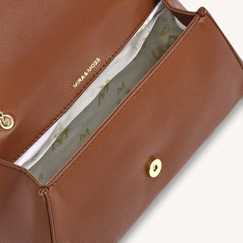 Brown leather handbag with gold accents on a light gray background