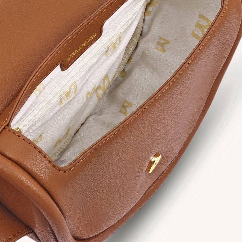 Close-up of a brown leather bag with gold logo on a light gray background