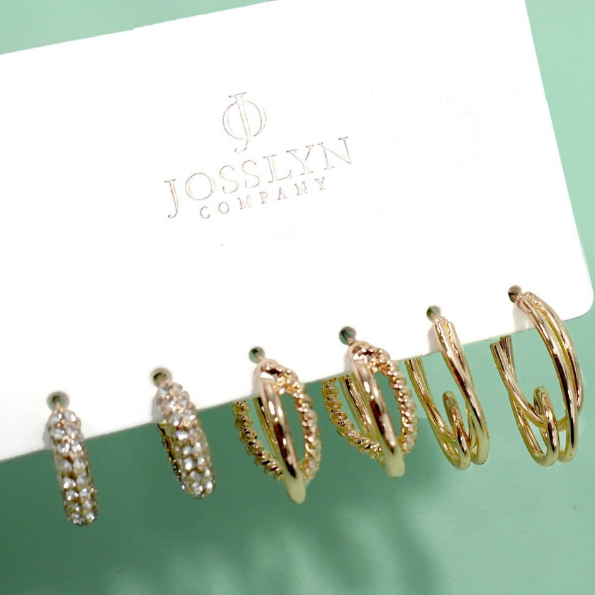 Set of gold hoop earrings on a Jocelyn Company card against a green background