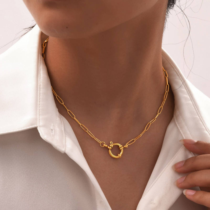 Gold necklace worn by a person with a white shirt