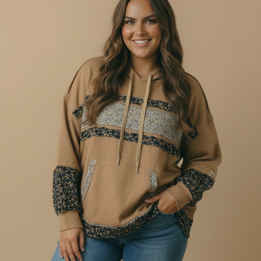 Woman wearing a beige hoodie with patterned sleeves and blue jeans on a beige background