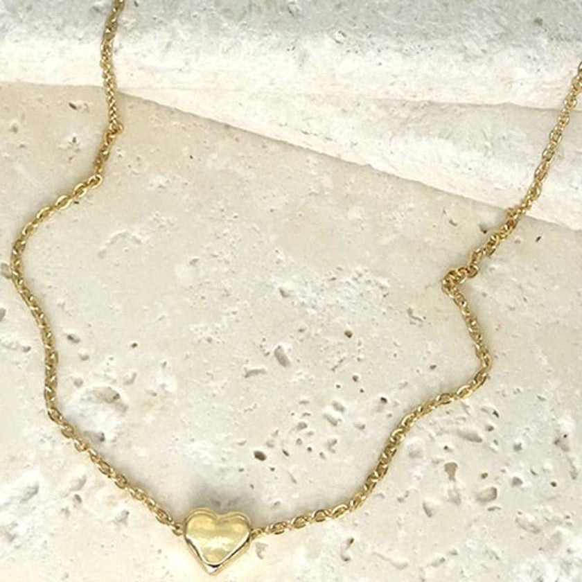 Gold heart-shaped pendant necklace on a textured surface