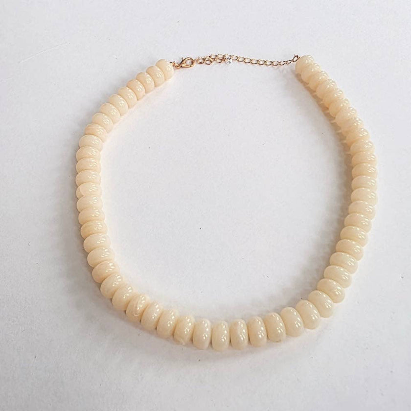Beige beaded necklace on a light gray background