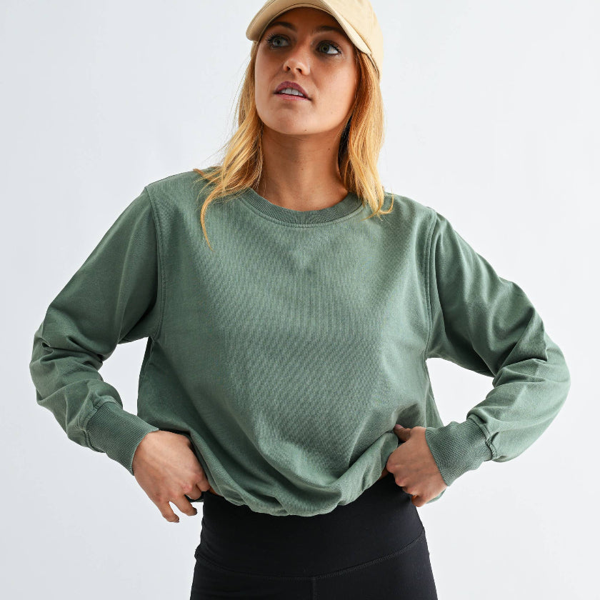 Woman wearing a green sweatshirt and black leggings on a white background