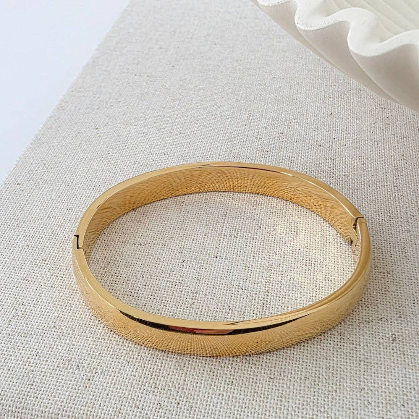 Gold bangle on a textured fabric surface