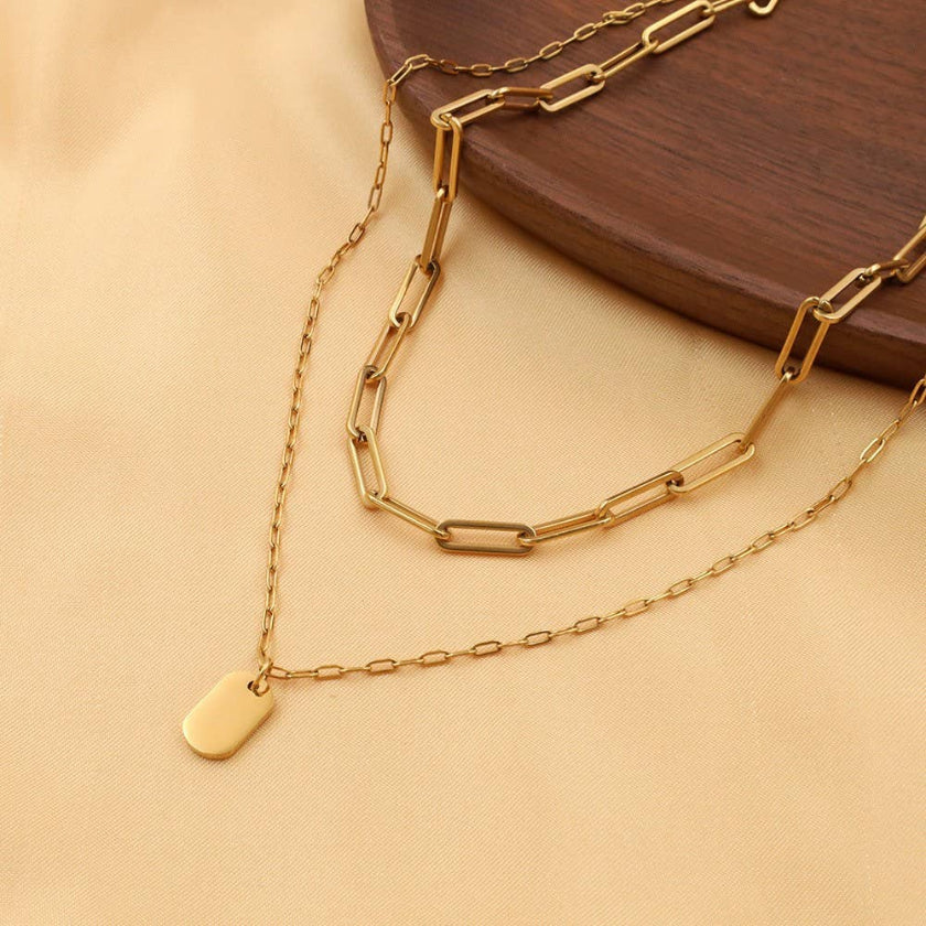 Gold chain necklace with a tag on a beige surface