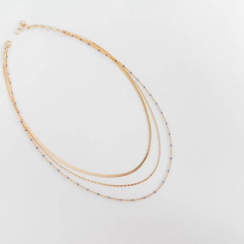 Two gold necklaces on a light gray background