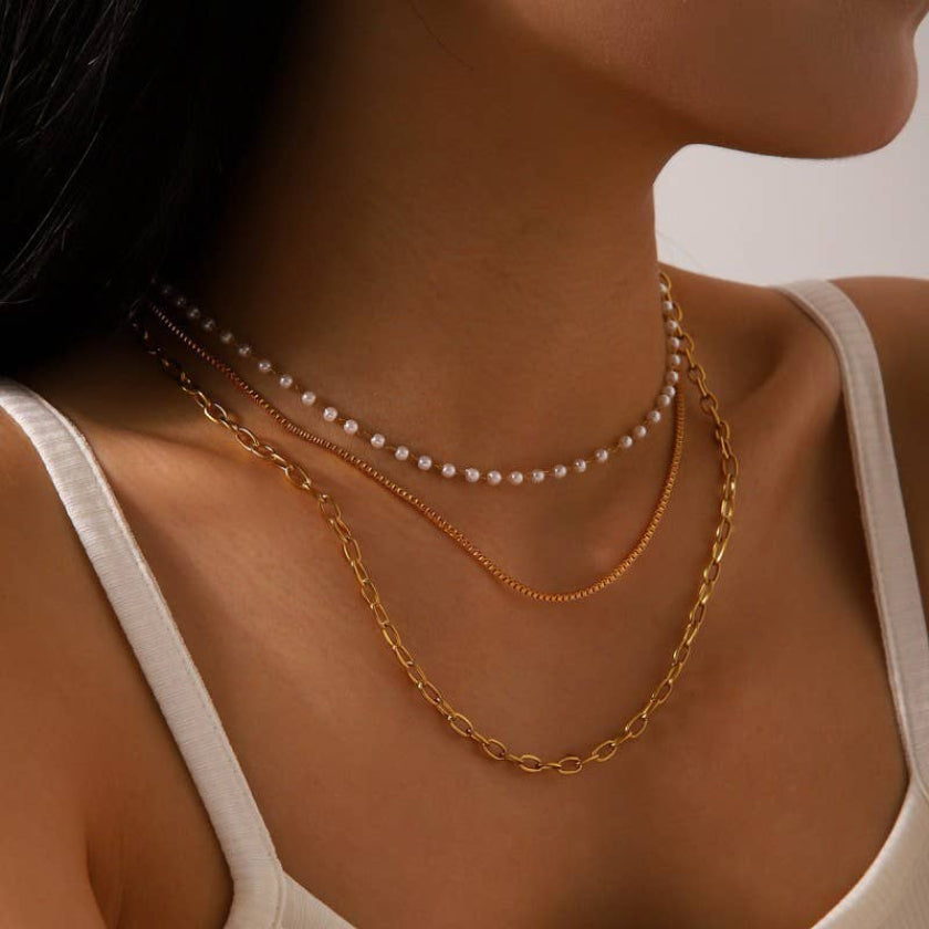 Close-up of a woman wearing two necklaces with a plain background