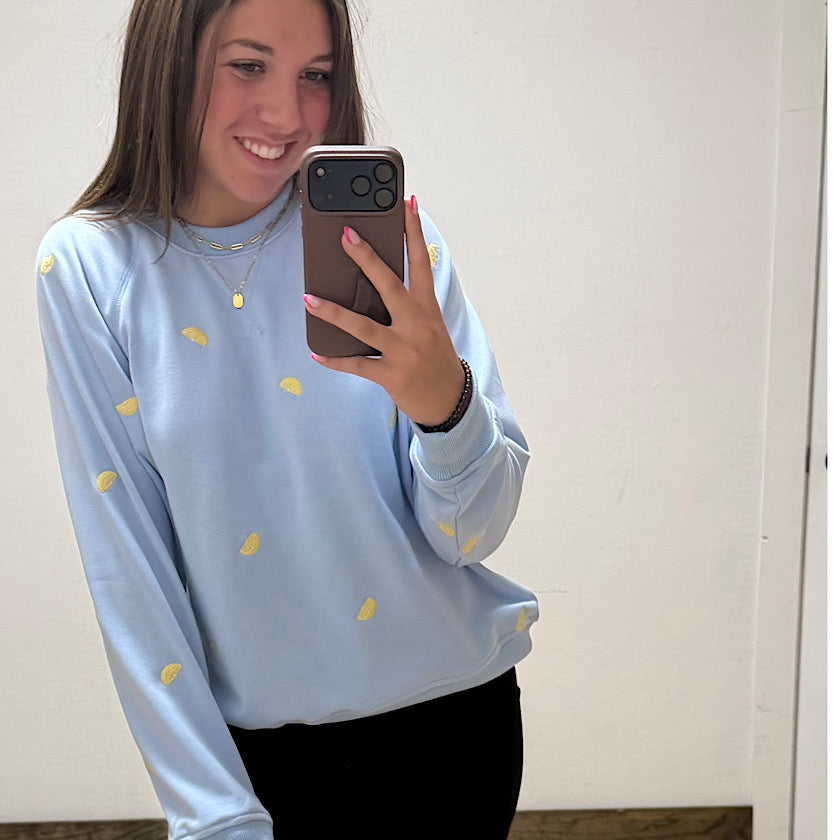 Person wearing a light blue sweatshirt with yellow polka dots, taking a mirror selfie.