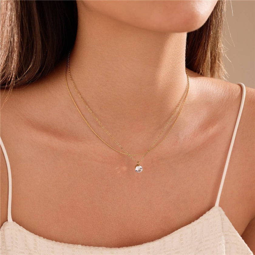 Close-up of a person wearing a delicate gold necklace with a small pendant.