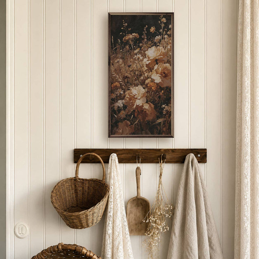Decorative wall with floral painting, wicker basket, and hooks with items on a beige paneled wall.