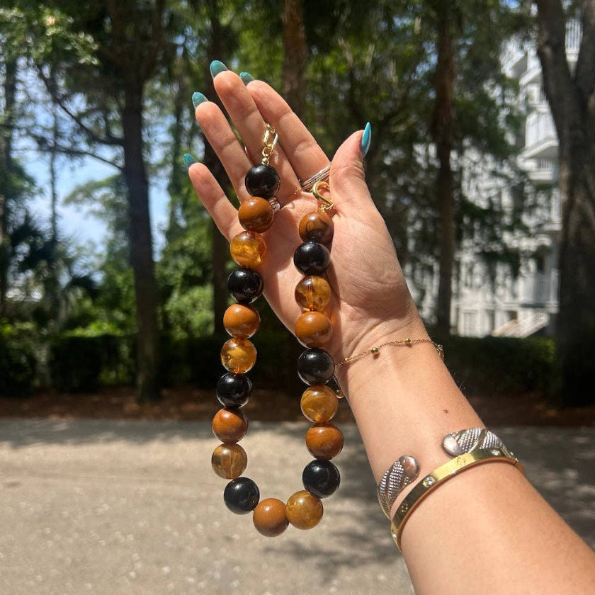 Hand holding a beaded necklace with a blurred outdoor background