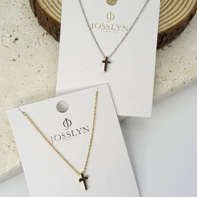 Two gold necklaces with cross pendants on JOSSLYN branded cards, displayed against a neutral background.