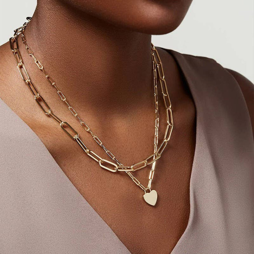Gold chain necklace with a heart pendant on a neutral background