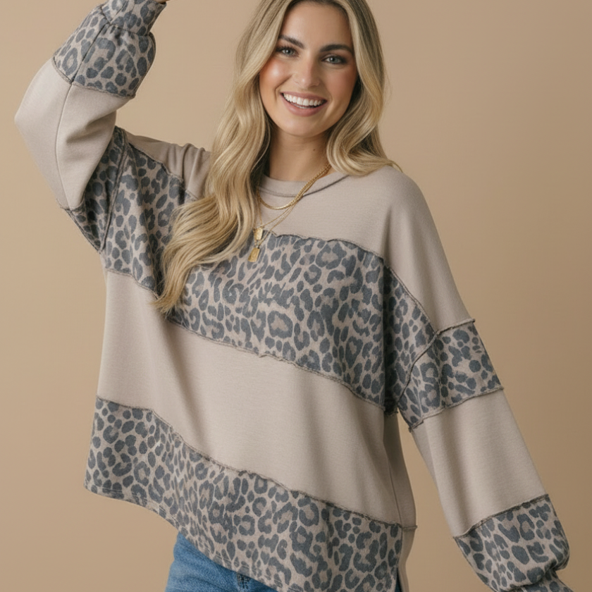 Woman wearing a beige and leopard print long-sleeve top with blue jeans on a beige background