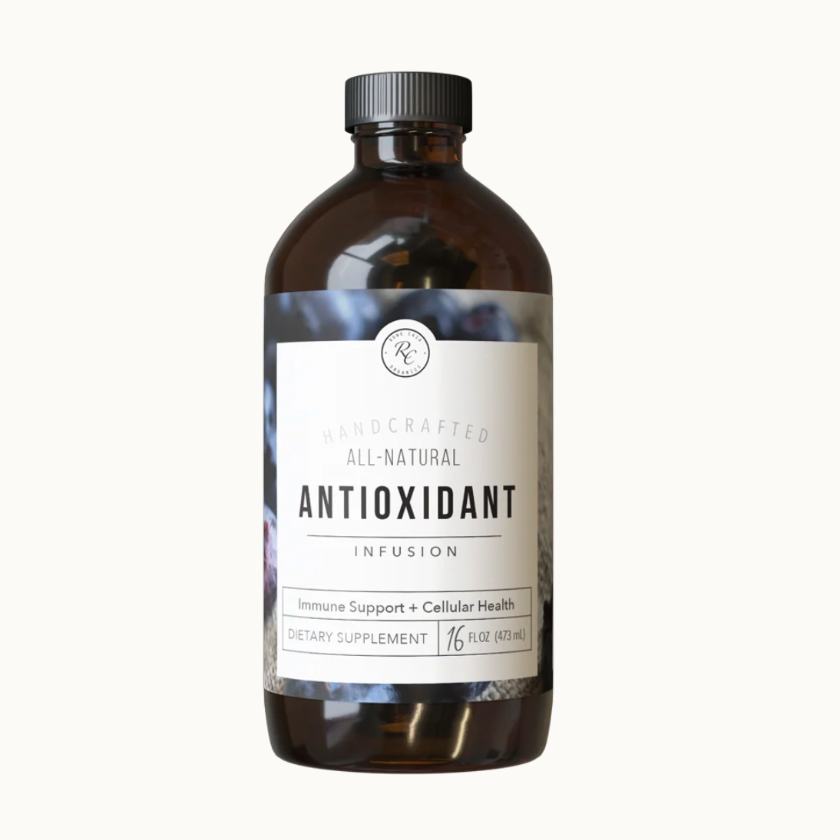 An amber glass bottle of KQ Natural Antioxidant Infusion dietary supplement with a black ribbed cap and a white label, centered on a clean off-white background.