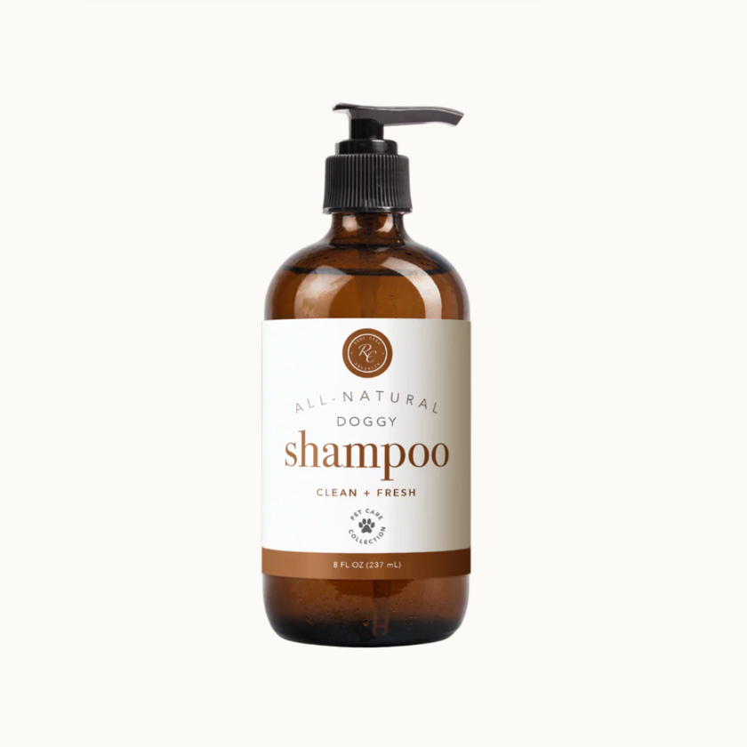 An 8 fl oz amber glass pump bottle of All-Natural Doggy Shampoo on a clean off-white background.
