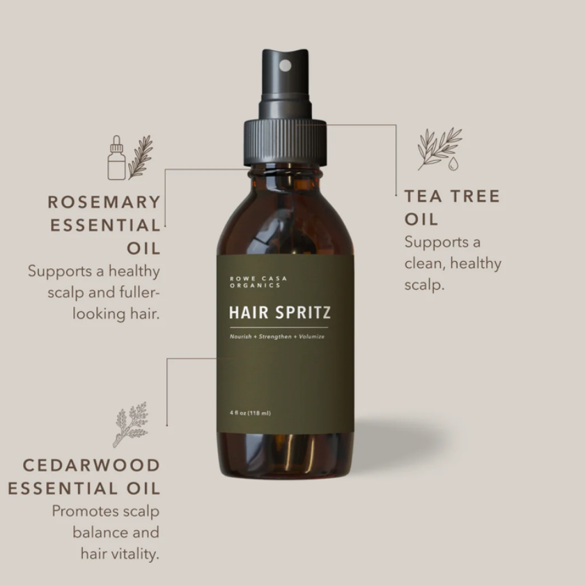 An amber glass spray bottle labeled 'Some Cakes Organics Hair Spritz' centered on a warm beige background, with callout lines and text describing rosemary essential oil, tea tree oil, and cedarwood essential oil benefits.