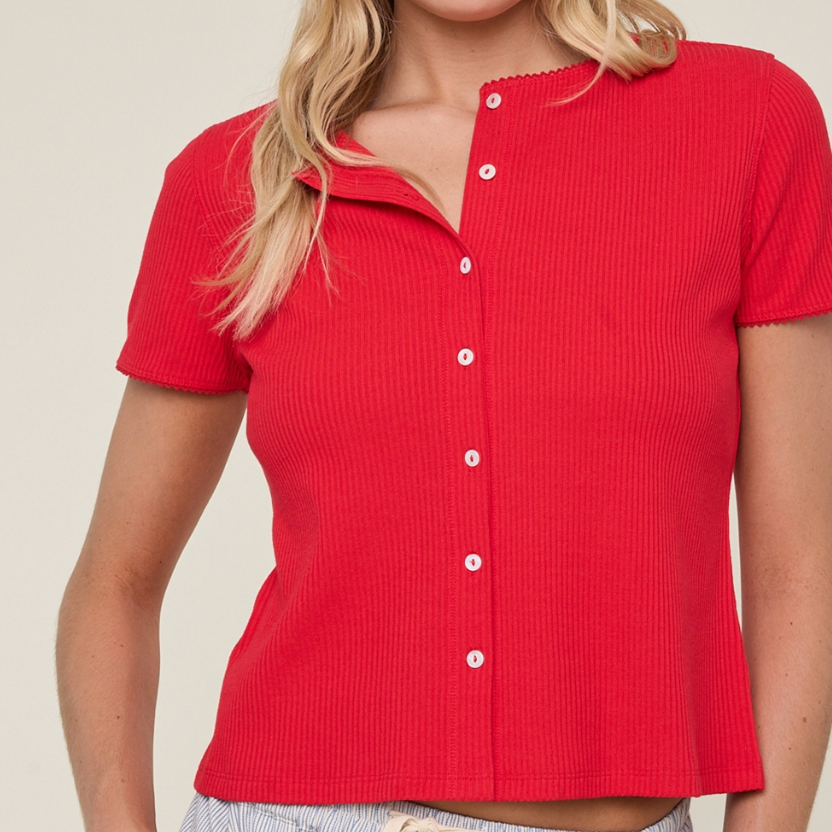 Woman wearing a red button-up shirt and navy cap with a logo on a beige background