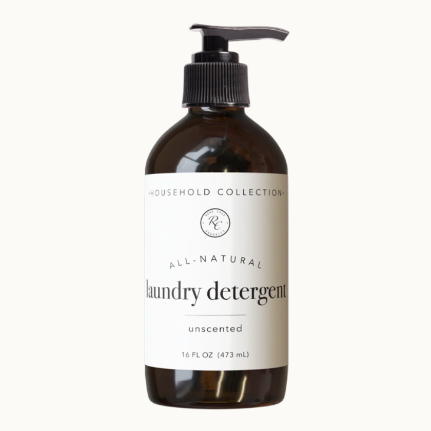 A 16 fl oz amber glass bottle of laundry detergent with a black pump dispenser and a white label. The label reads 'HOUSEHOLD COLLECTION', 'ALL-NATURAL', 'laundry detergent', and 'unscented'.
