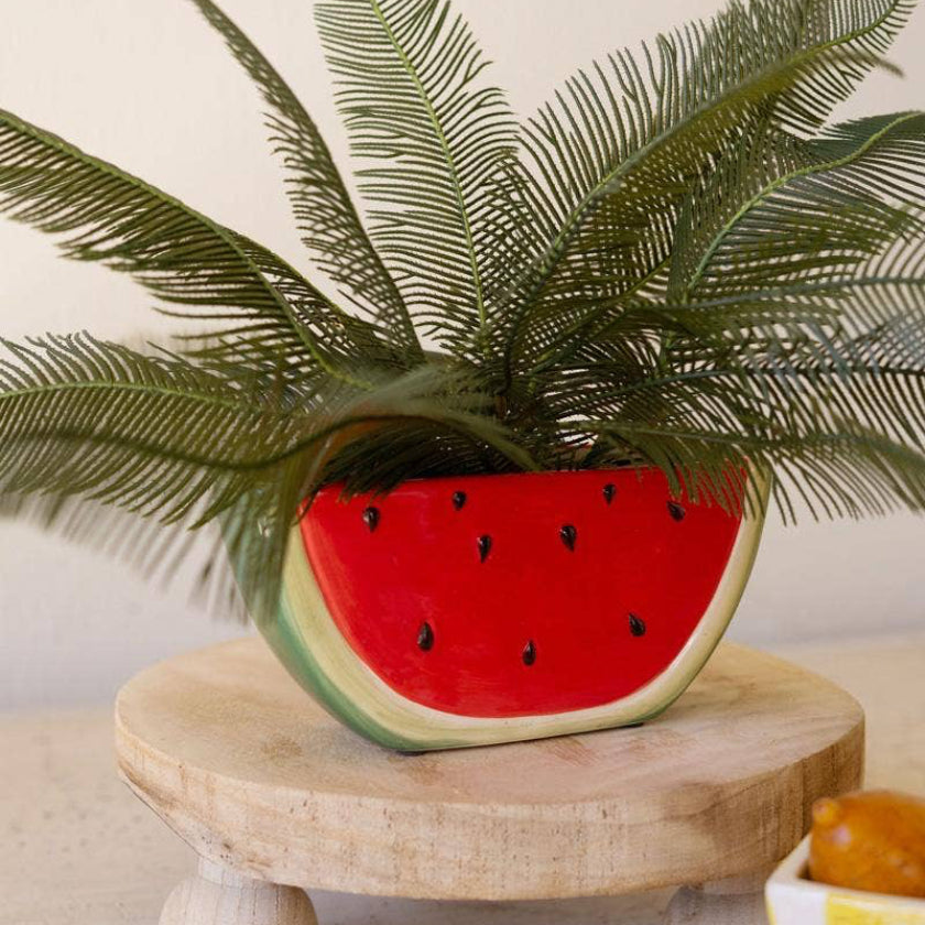 Decorative item with a watermelon-shaped planter on a wooden stand.