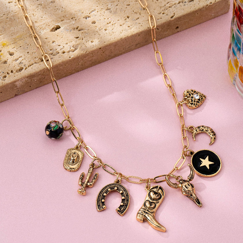 Necklace with various charms on a pink surface