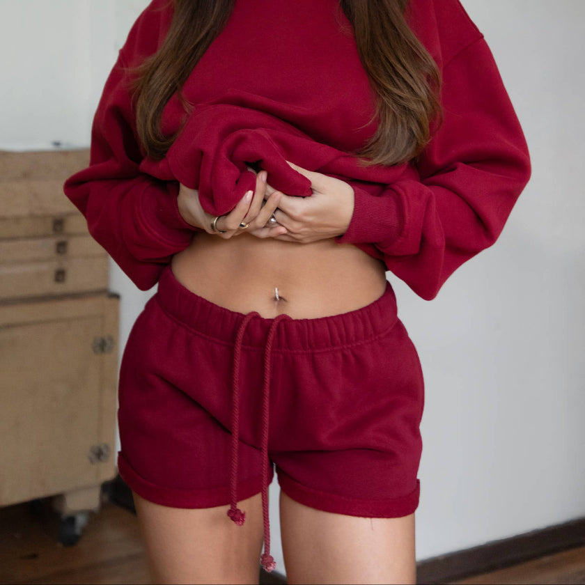 Woman wearing a red tracksuit standing indoors with a neutral background