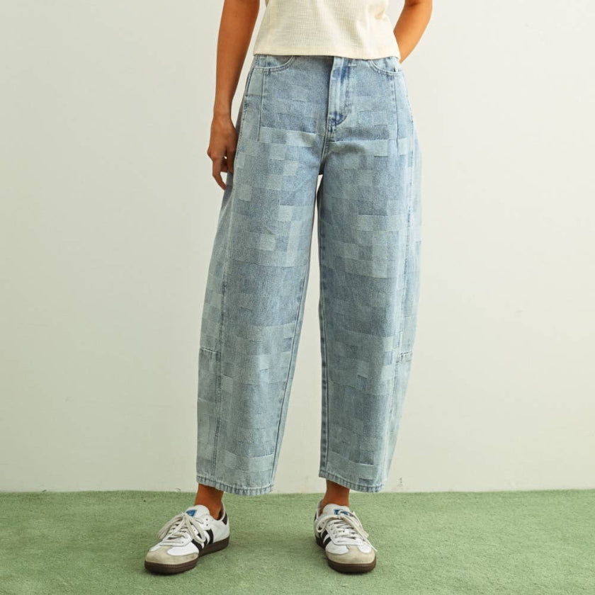 Woman wearing a white tank top and light blue jeans on a plain background