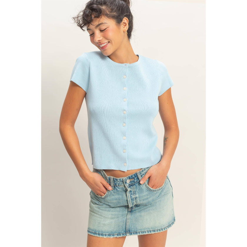 Woman wearing a light blue top and denim skirt against a plain background