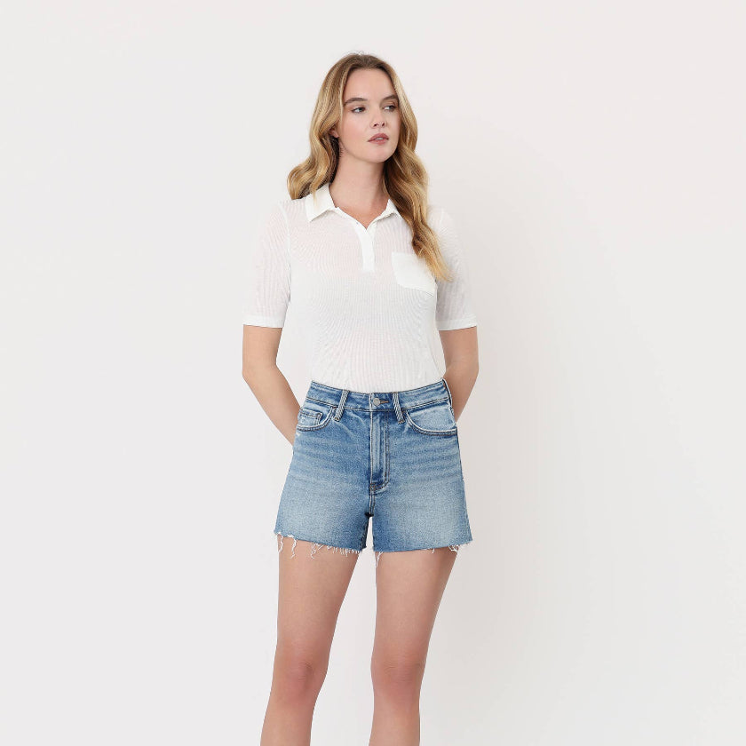 Woman wearing a white polo shirt and blue denim shorts on a white background