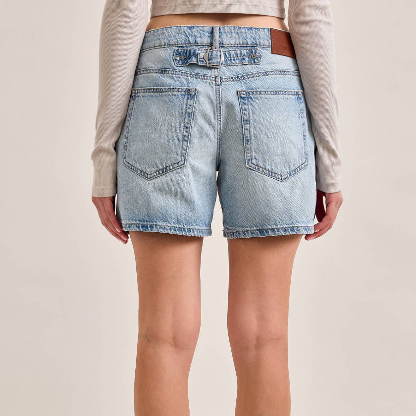 Light blue denim shorts worn by a person on a beige background