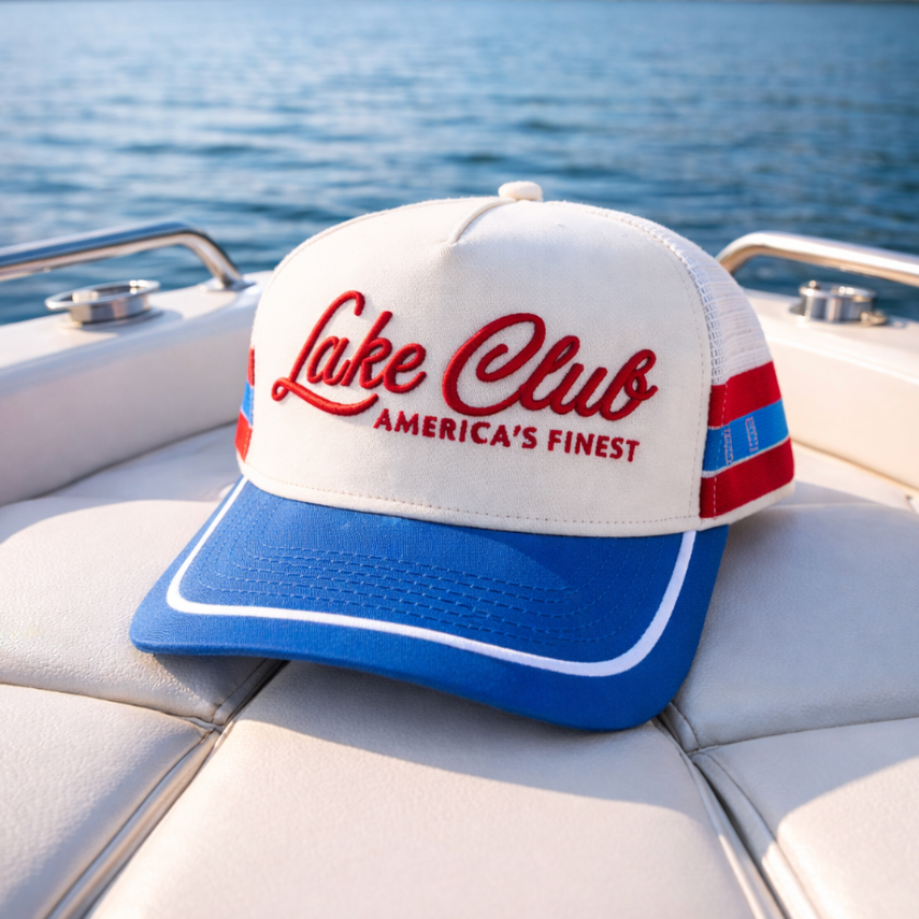 Lake Club cap on a boat seat with a lake and trees in the background