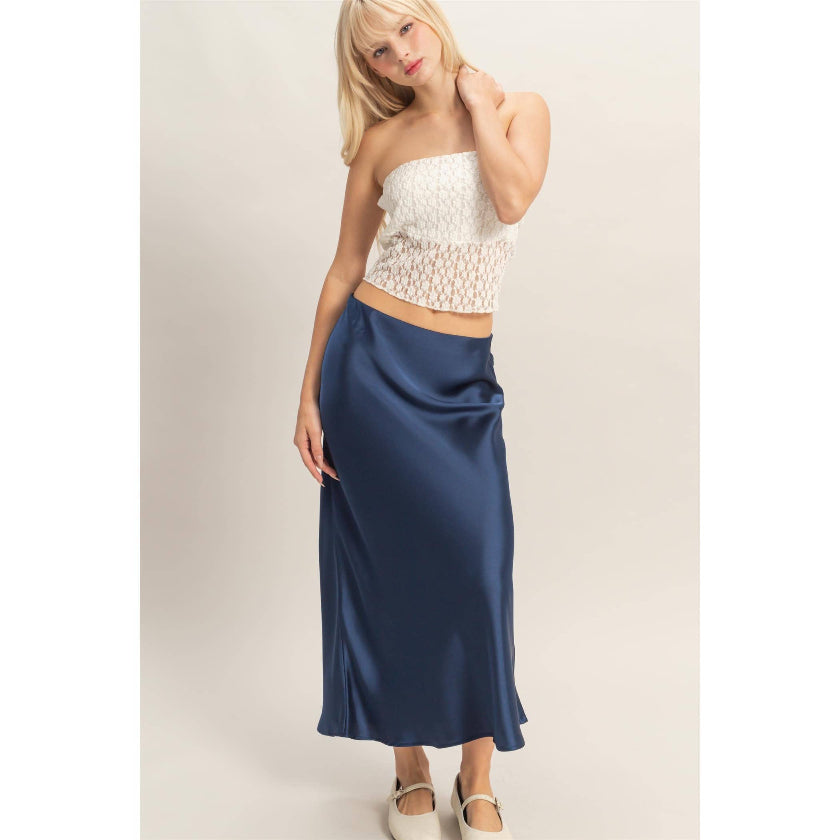 Woman wearing a white top and blue skirt on a beige background
