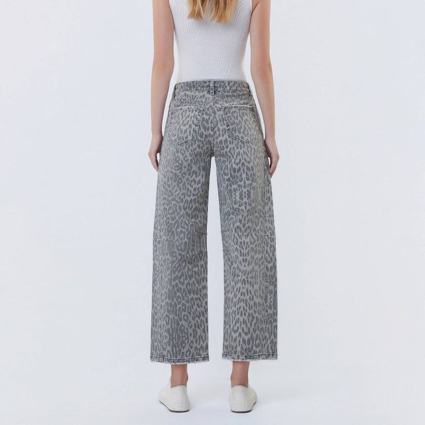 Woman wearing a white sleeveless top and gray leopard print pants on a white background